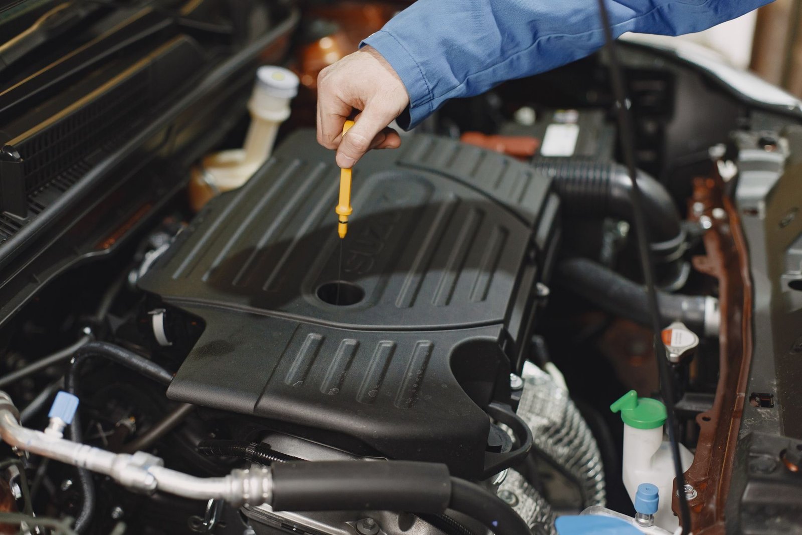 A hand pulls the dipstick out of the engine